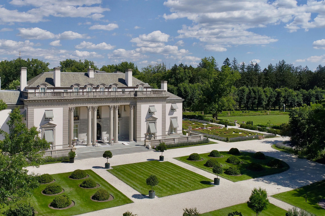 A view from above the Nemours Estate on a sunny day that shows the mansion building and some of the Gardens and woodlands. 