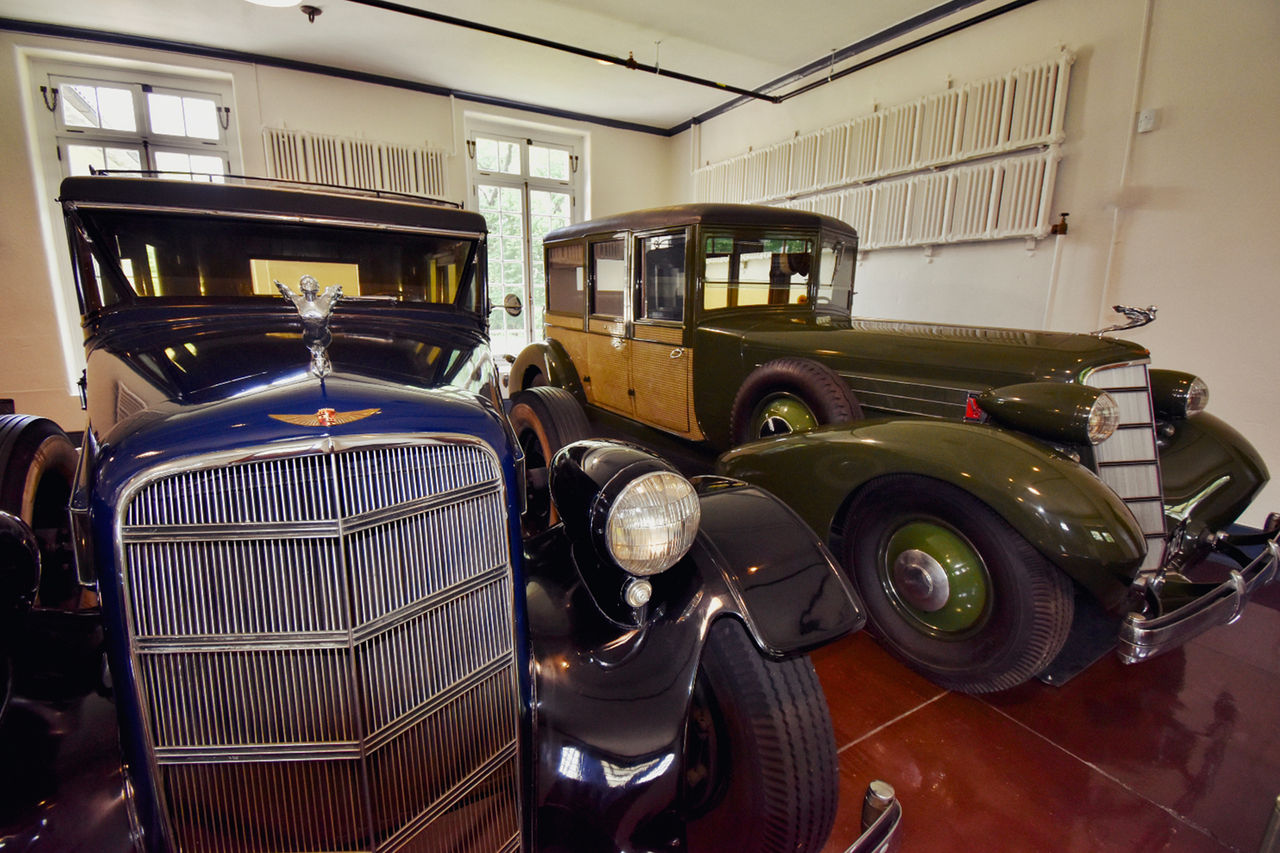 Two classic Cadillacs are parked next to each other inside the Chauffeur's Garage. 