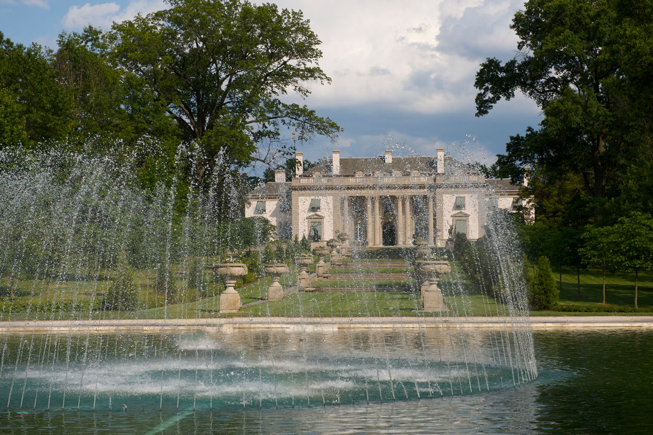A sunny day next to the Reflecting Pool and fountain, with the mansion building in the distance.