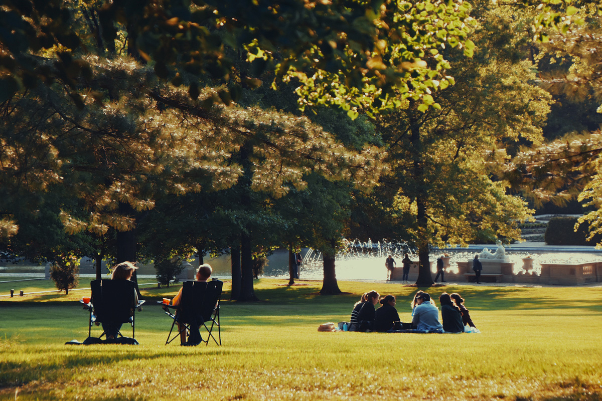 A couple relaxing in chairs while a nearby families sits together enjoying an evening at the Nemours Estate.